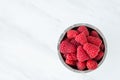 Bowl of fresh red raspberries for dessert, stainless steel bowl, white marble background Royalty Free Stock Photo