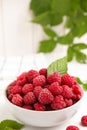 Bowl of fresh ripe raspberries with green leaf on white table, space for text Royalty Free Stock Photo