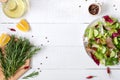 Bowl of fresh salad, rosemary, lemon, spices and oil on white wooden table. Royalty Free Stock Photo