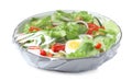 Bowl of fresh salad wrapped with transparent plastic stretch film isolated on white