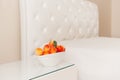 Bowl of fresh sweet ripe fruits peaches on table near empty white bed Royalty Free Stock Photo