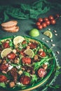 Bowl of fresh vegetable salad: arugula, fresh and dried cherry tomatoes, pine nuts and cheese on a green background Royalty Free Stock Photo