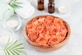 Bowl with fresh wet rose and essential oil bottle for spa, wellness and aromatherapy.