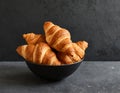 Bowl of freshly baked croissants, on a dark gray background. Delicious breakfast. Royalty Free Stock Photo