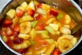 A bowl of fruit salad made of slices of bananas, strawberry, cantaloupe, apples and juice of mango and orange mixed together,