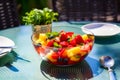 Bowl of fruit is sitting on table next to plate of salad. Generative AI