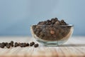 Bowl full of black pepper grains on a bamboo board Royalty Free Stock Photo