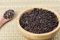 Bowl full of black peppercorns on a bamboo background Royalty Free Stock Photo