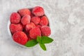 A bowl full of frozen strawberries with fresh mint leaves on a gray background with place for text