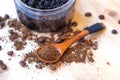 Bowl full of ground coffee scrub with olive oil and salt as homemade facial and body scrub with spoon on wooden background.