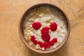 Bowl full of oatmeal cooked with milk and pear pieces and flavored with raspberry fresh smile