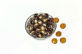 A bowl full of peeled longan fruit and some unpeeled longan on white background