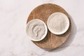 Bowl with gray cosmetic clay cream and clay powder on wooden tray