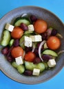 A bowl of Greek salad against a blue background Royalty Free Stock Photo