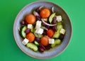 A bowl of Greek salad against a green background Royalty Free Stock Photo