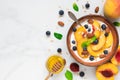 Bowl of greek yogurt with peach, oats, nuts, mint, honey and blueberries with a spoon for healthy breakfast. top view Royalty Free Stock Photo