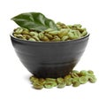 Bowl with green coffee beans and fresh leaf on white background Royalty Free Stock Photo