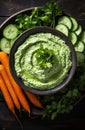 a bowl of green dip with carrots and cucumbers