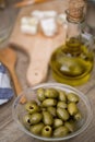 Bowl of green olives and bottle of olive oil over wooden table