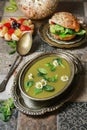 Bowl of green pea soup, fruit salad and vege burger bun with vegetables