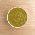 Bowl of green pea soup on a wood table top