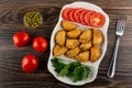 Bowl with green peas, tomatoes, partitioned dish with patties, parsley, slices of tomato, fork on table. Top view Royalty Free Stock Photo