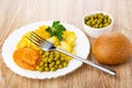 Bowl with green peas, plate with fried potato, squash caviar, green peas, bread, fork on table