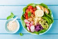 Bowl with grilled chicken meat, bulgur and fresh vegetable salad of radish, tomatoes, avocado, kale and spinach leaves