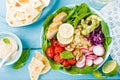 Bowl with grilled chicken meat, bulgur and fresh vegetable salad of radish, tomatoes, avocado, kale and spinach leaves