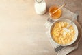 Bowl with healthy cornflakes, milk and honey on light table