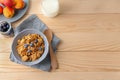 Bowl with healthy cornflakes, milk and peaches on wooden table