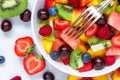 Bowl of healthy fresh fruit salad with fork on white marble background. healthy food. close up Royalty Free Stock Photo