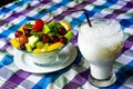 Bowl of healthy fresh fruit salad and milk on pattern of Thai hand made fabric background. Royalty Free Stock Photo