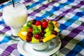 Bowl of healthy fresh fruit salad and milk on pattern of Thai hand made fabric background. Royalty Free Stock Photo