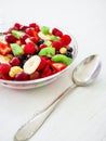 Bowl of healthy fresh fruit salad and silver spoon on white wooden background. Top view. Royalty Free Stock Photo