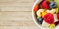 Bowl of healthy fresh fruit salad on wooden table. top view copy space. modern fruit salad light wooden background, Royalty Free Stock Photo