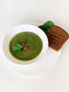 Bowl of healthy green soup with fresh spinach and fried champignons with grilled bread on white table Royalty Free Stock Photo