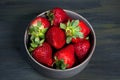 Bowl with healthy strawberries, grouped in the middle on a dark table