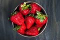 Bowl with healthy strawberries, grouped in the middle on a dark table