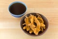 Bowl of herbal sliced dried Lingzhi mushroom next to hot Reishi