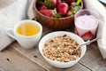 A bowl of homemade granola with yogurt and fresh strawberries on a wooden background. Healthy breakfast with green tea Royalty Free Stock Photo