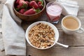 A bowl of homemade granola with yogurt and fresh strawberries on a wooden background. Healthy breakfast with green tea Royalty Free Stock Photo