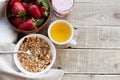 A bowl of homemade granola with yogurt and fresh strawberries on a wooden background. Healthy breakfast with green tea Royalty Free Stock Photo