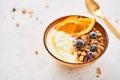 Bowl of homemade granola with yogurt, honey, fresh orange and frozen blueberries Royalty Free Stock Photo