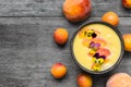 Bowl of homemade yellow smoothie with fresh mango, peaches and apricots