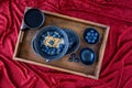 Bowl of hot oatmeal with blueberries and walnuts, black bowl and plate, black spoon, small topping bowls, cup of tea Royalty Free Stock Photo