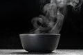 Bowl of hot steam of hot soup with smoke. black ceramic bowl on dark background. Hot food. Culinary, cooking, concept Royalty Free Stock Photo