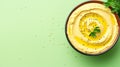 Bowl of hummus with greens and olive oil on plain background, copy space