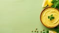 Bowl of hummus with greens on simple background