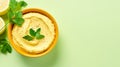 Bowl of hummus with greens on simple background